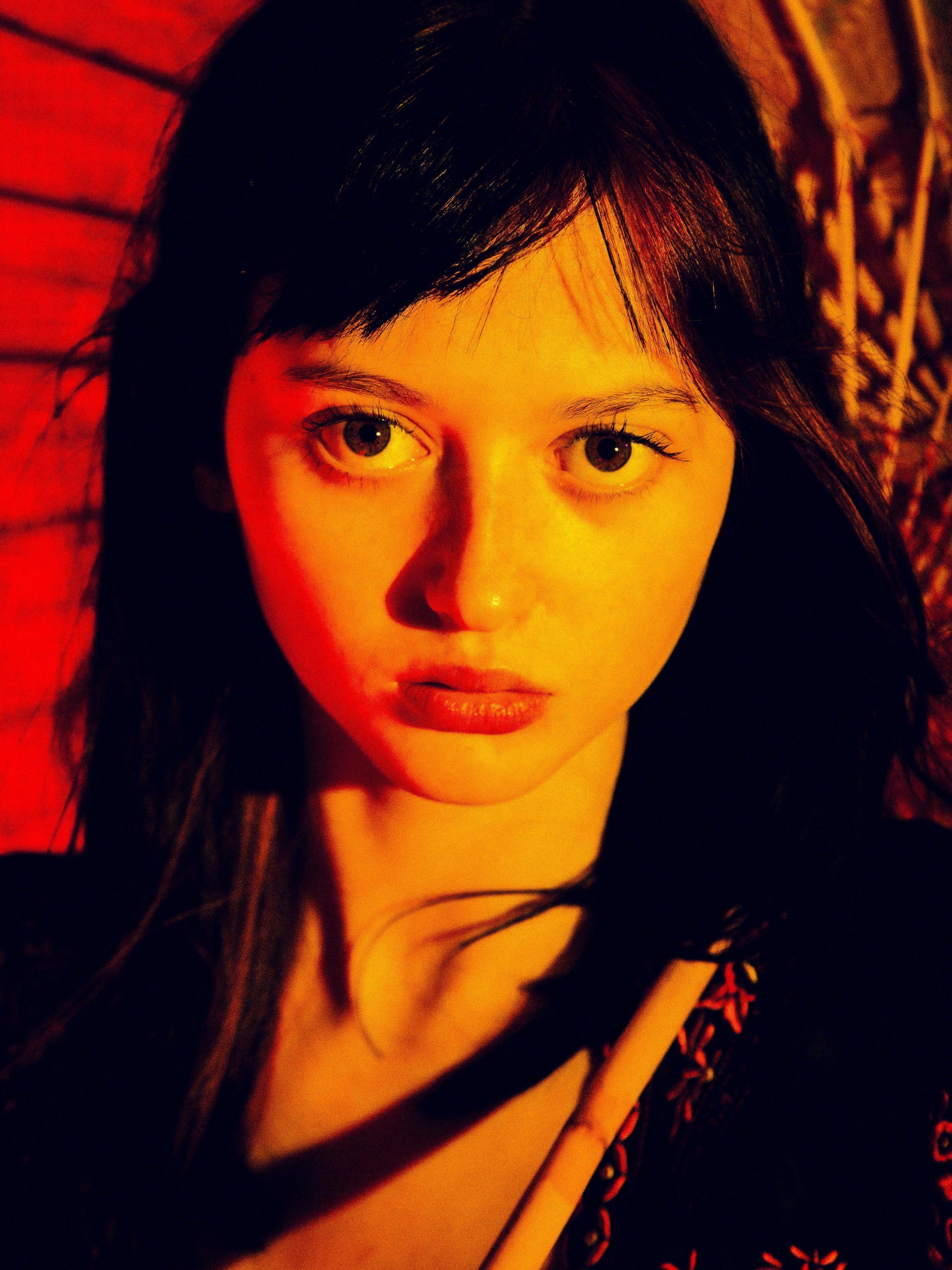 A dramatic portrait series in red lighting shows silhouetted features and dark shadows creating a moody atmosphere.