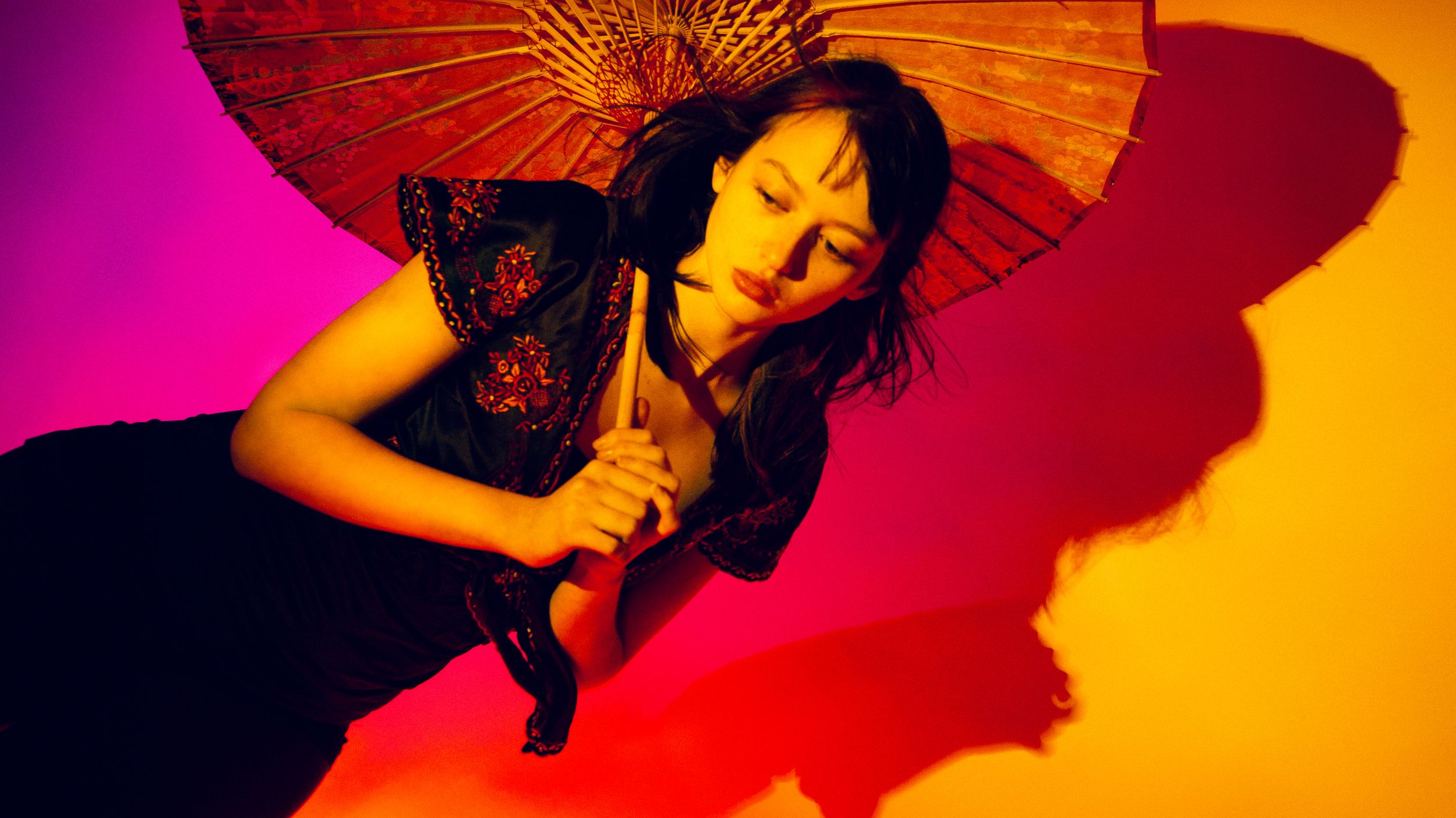 Abstract shapes in vibrant pink, orange and black form a flowing pattern against a gradient background.