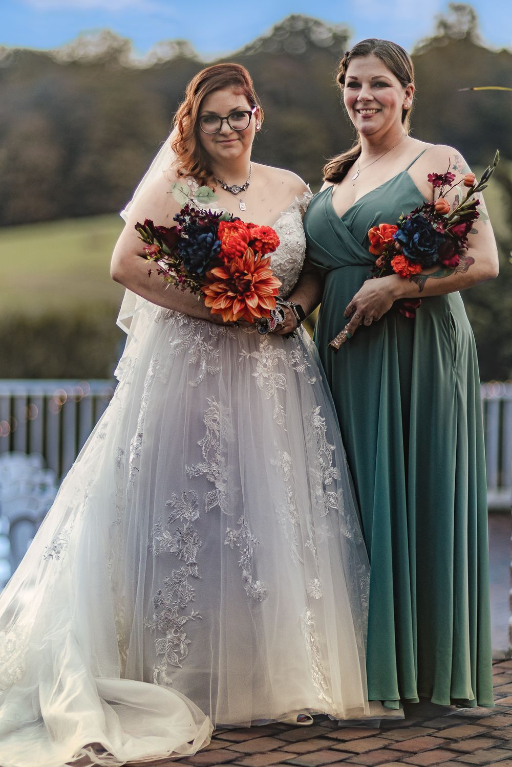 Wedding party photos showing bride in white lace gown with bridesmaid in emerald green dress holding bright bouquets.
