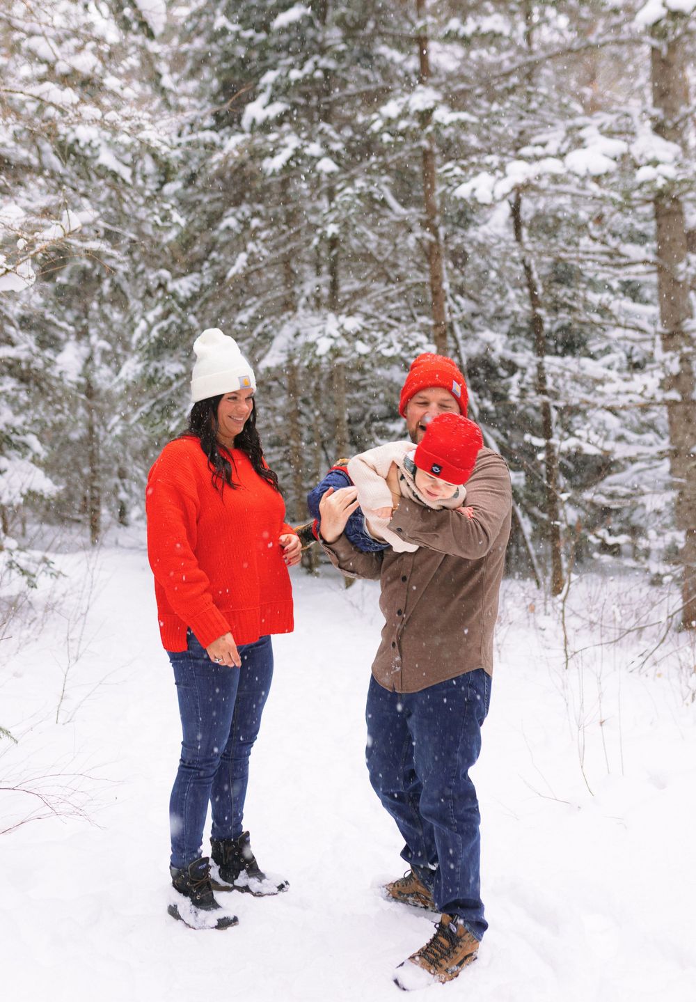 A playful sequence of two people having a snowball fight in a snowy forest setting wearing red and brown winter coats.