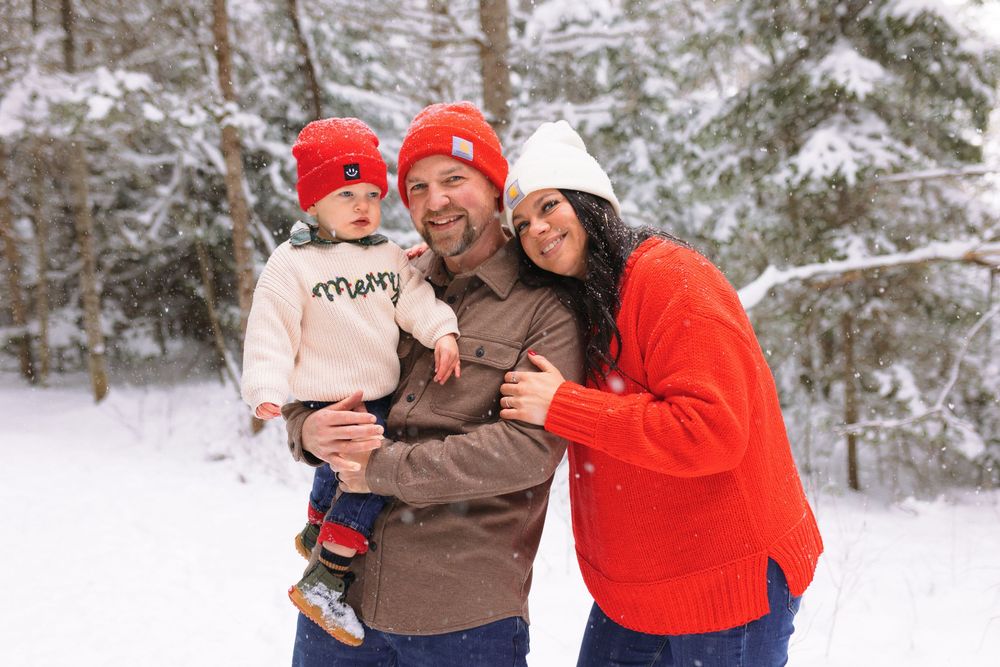 People enjoying a winter day outdoors in the snow, wearing warm coats and hats while embracing and smiling.