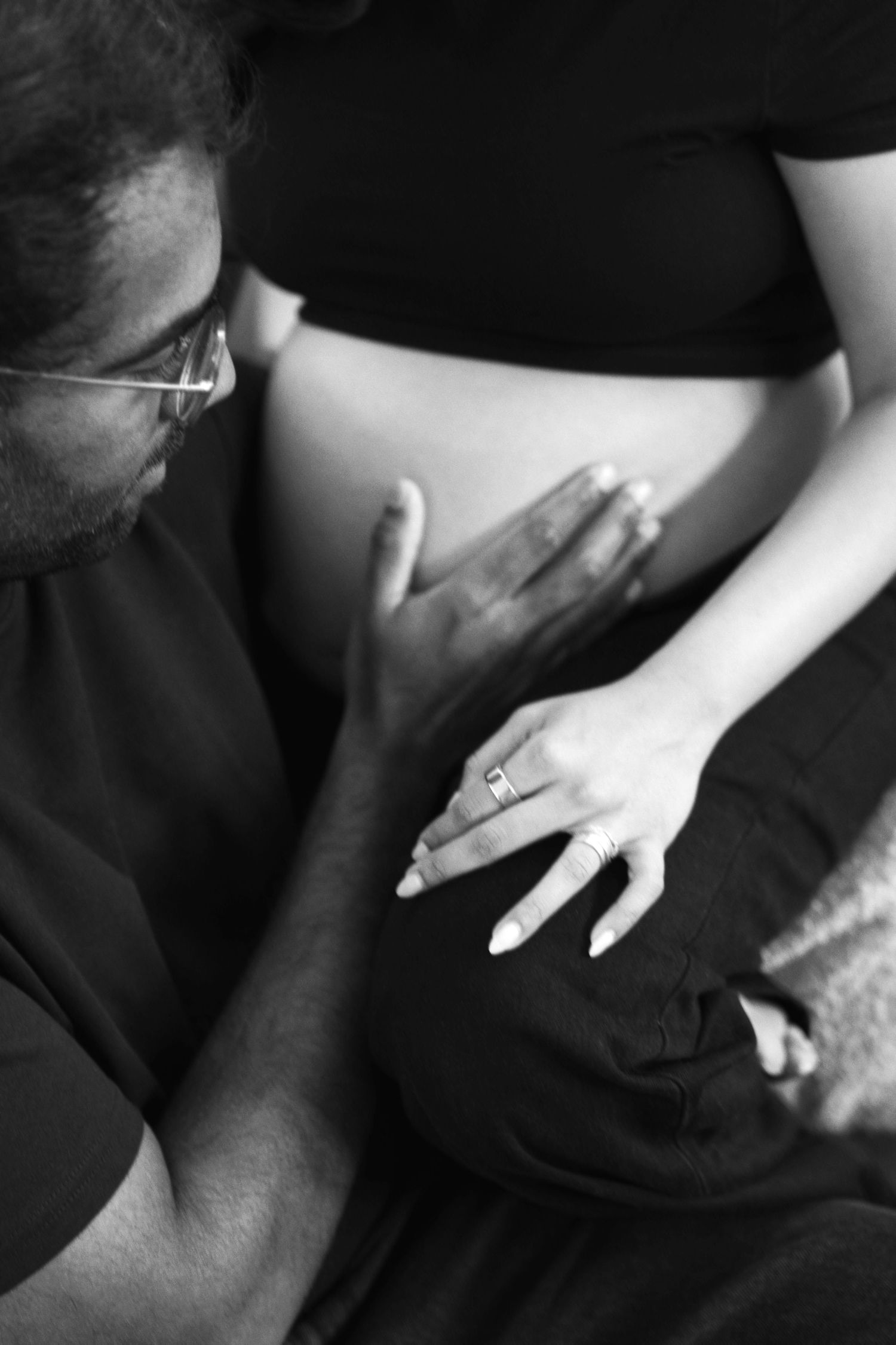 A black and white sequence showing hands with a ring interacting with dark fabric in an intimate close-up study.