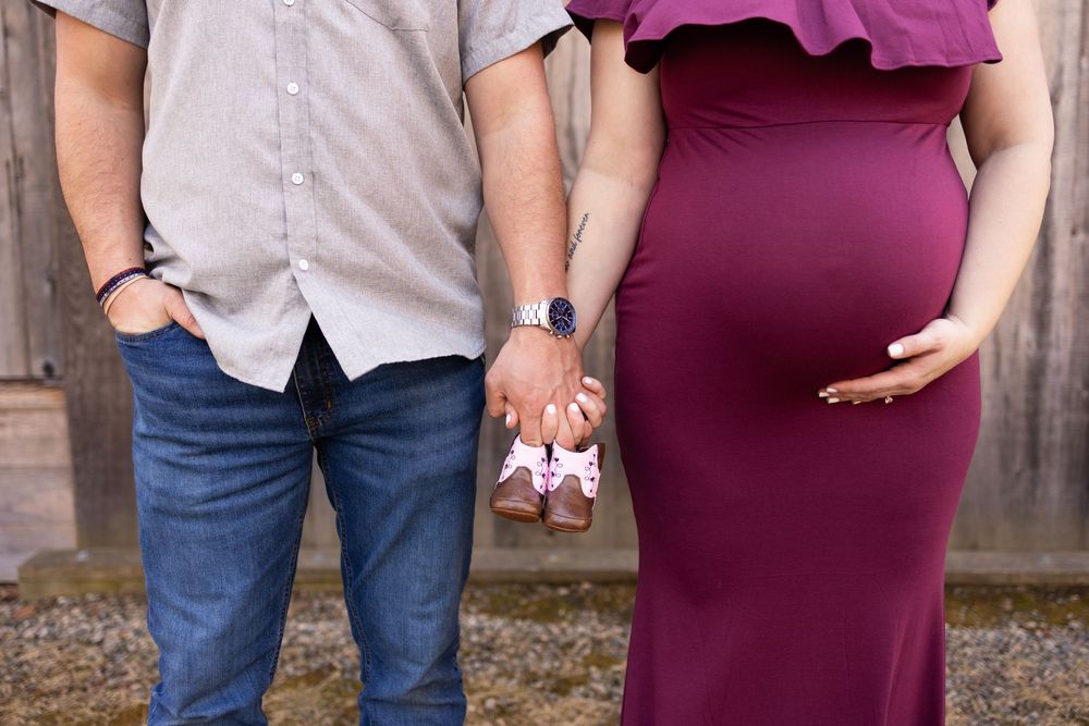 A couple in casual attire holds hands while standing outdoors in a romantic pose.