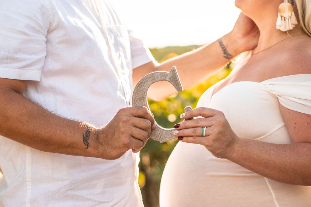 A couple in white attire holds green apples together during a romantic outdoor photoshoot at sunset.