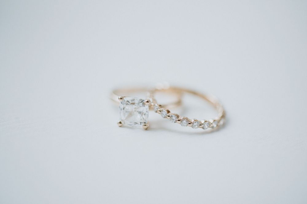A delicate rose gold engagement ring with a small diamond and twisted band design on white background.
