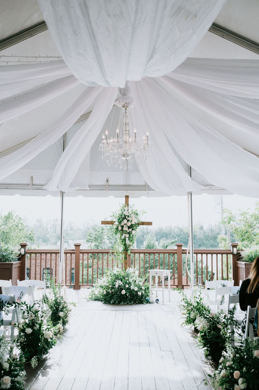 Elegant white draped tent ceiling with crystal chandeliers and floral arrangements for an outdoor wedding reception.