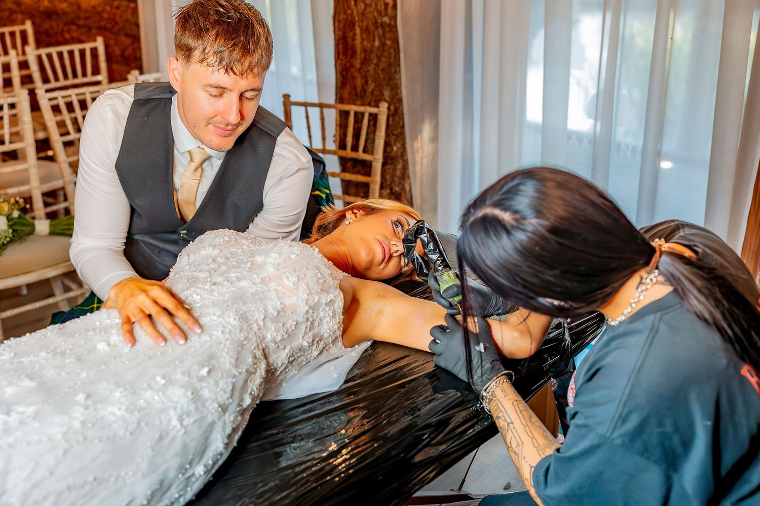 Unobtrusive wedding photography capturing a wedding couple getting matching tattoos.