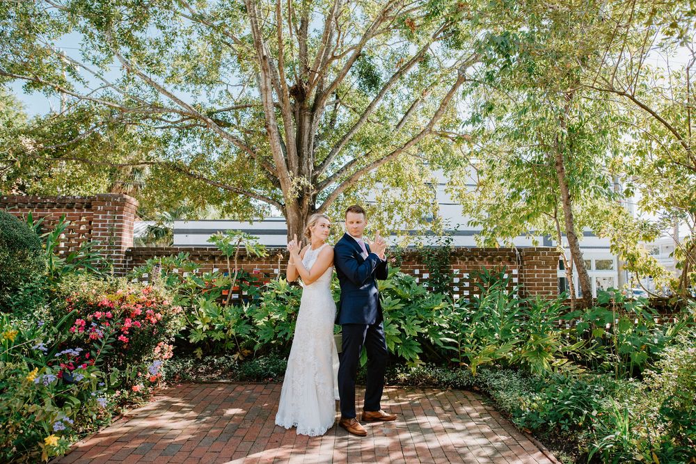 A wedding couple shares intimate moments under a lush garden archway with natural greenery and flowers.