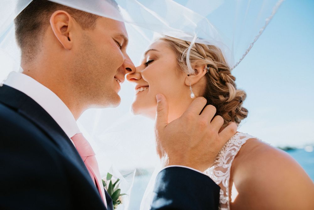 Close-up romantic moments captured against a bright blue sky on a sunny wedding day.