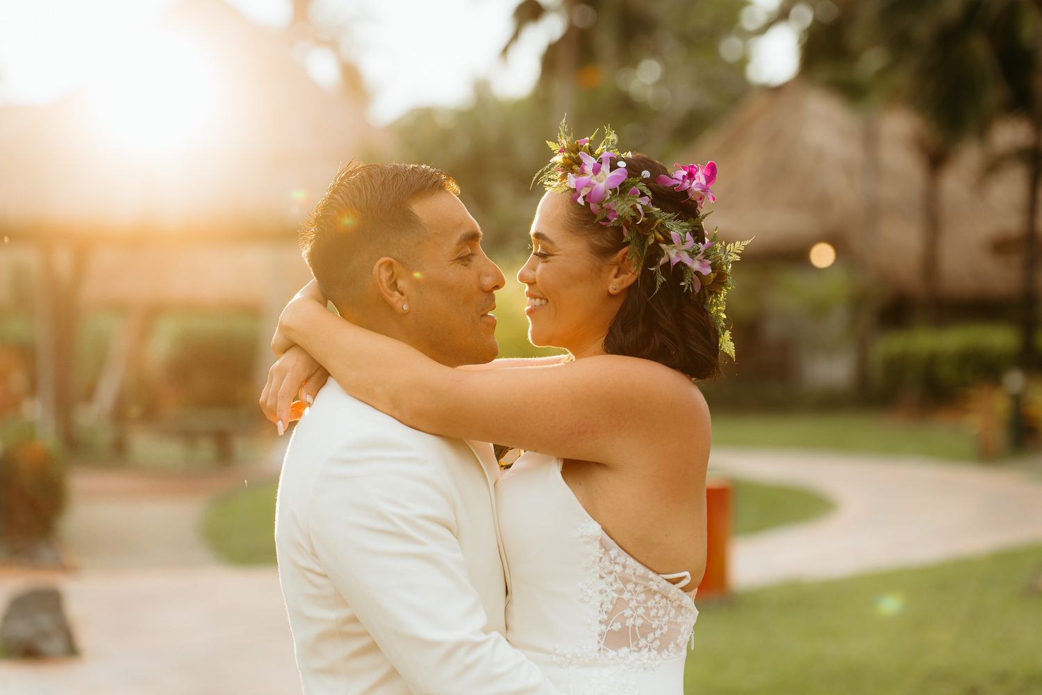 A romantic sunset wedding photo with a couple embracing in a garden setting during golden hour.