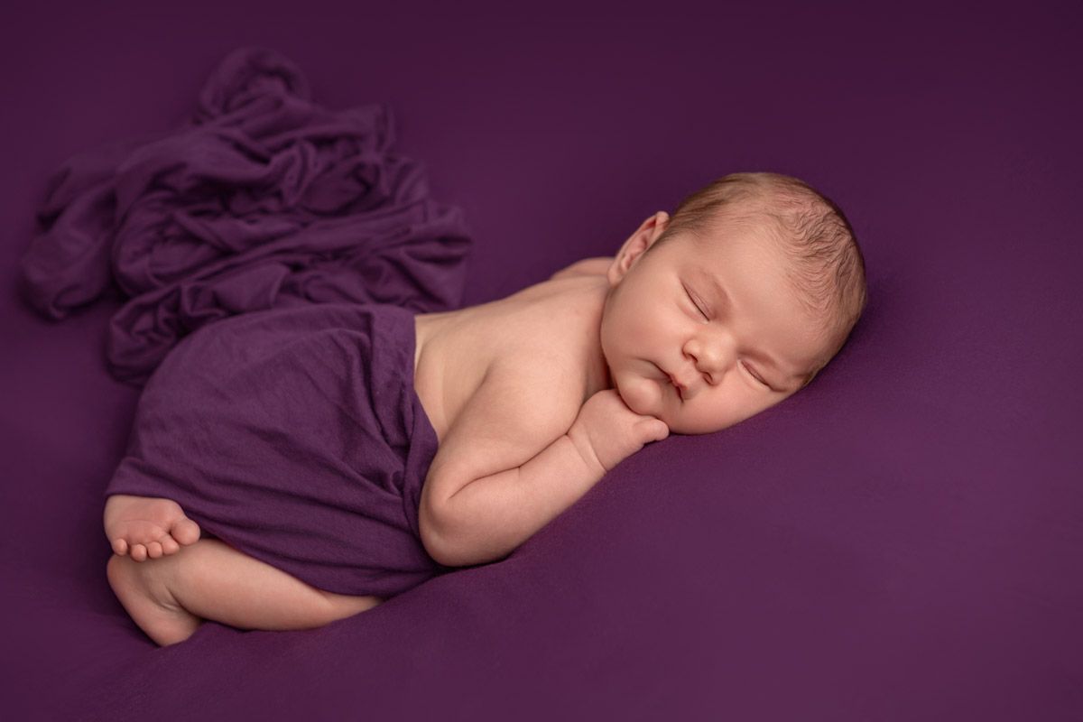 Newborn baby girl wrapped in dark purple