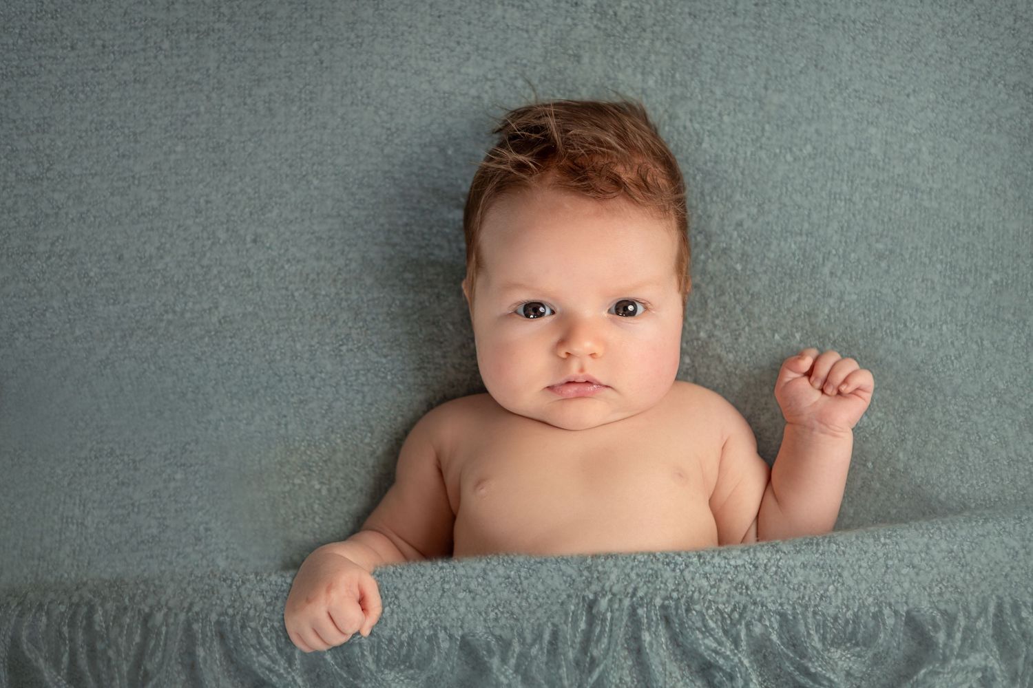 Newborn baby boy portrait in a green blanket