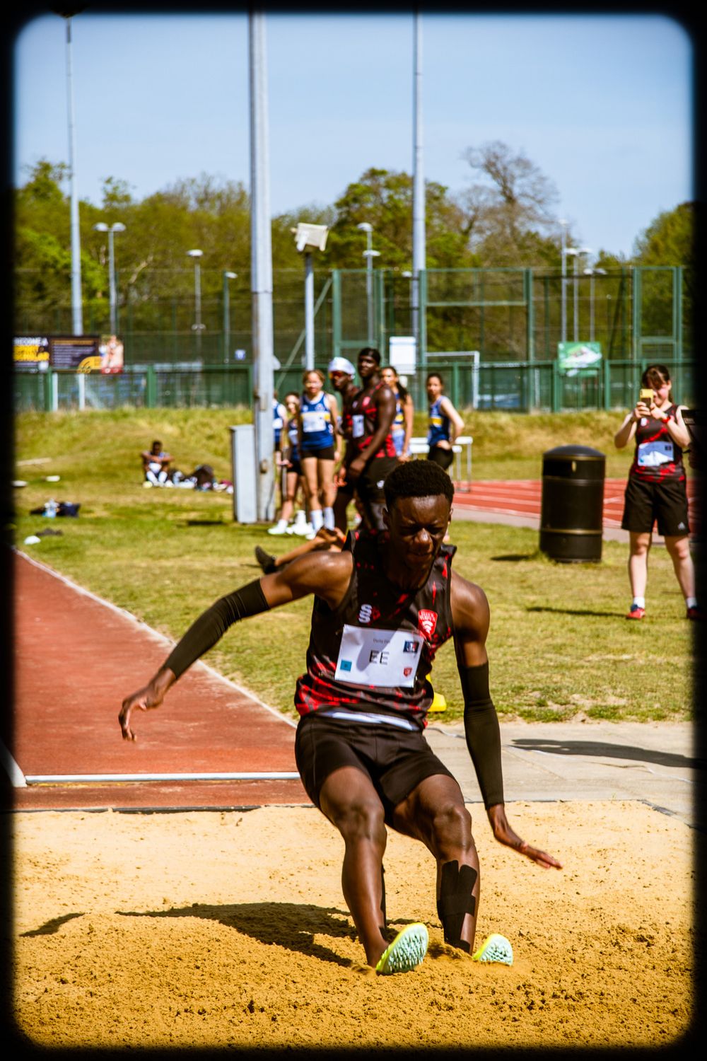 Sequential photos of an athlete performing a long jump at a track and field event, landing in the sand pit.