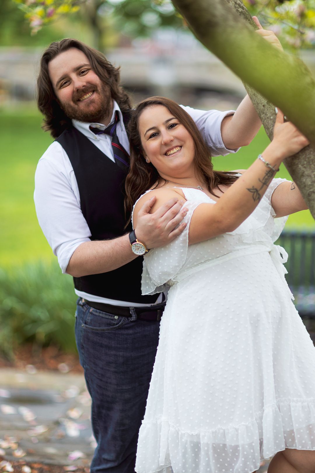 A couple in wedding attire dances and laughs together joyfully in an outdoor garden setting.