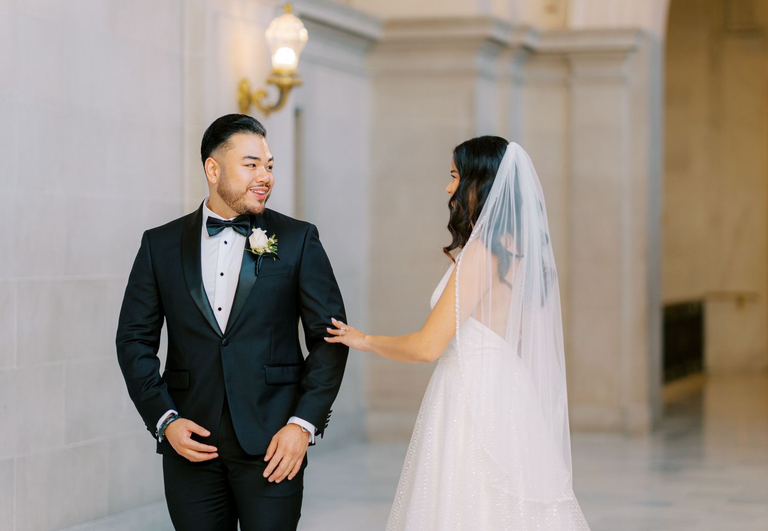 Couple sharing a moment in formal wedding attire in an elegant hallway.