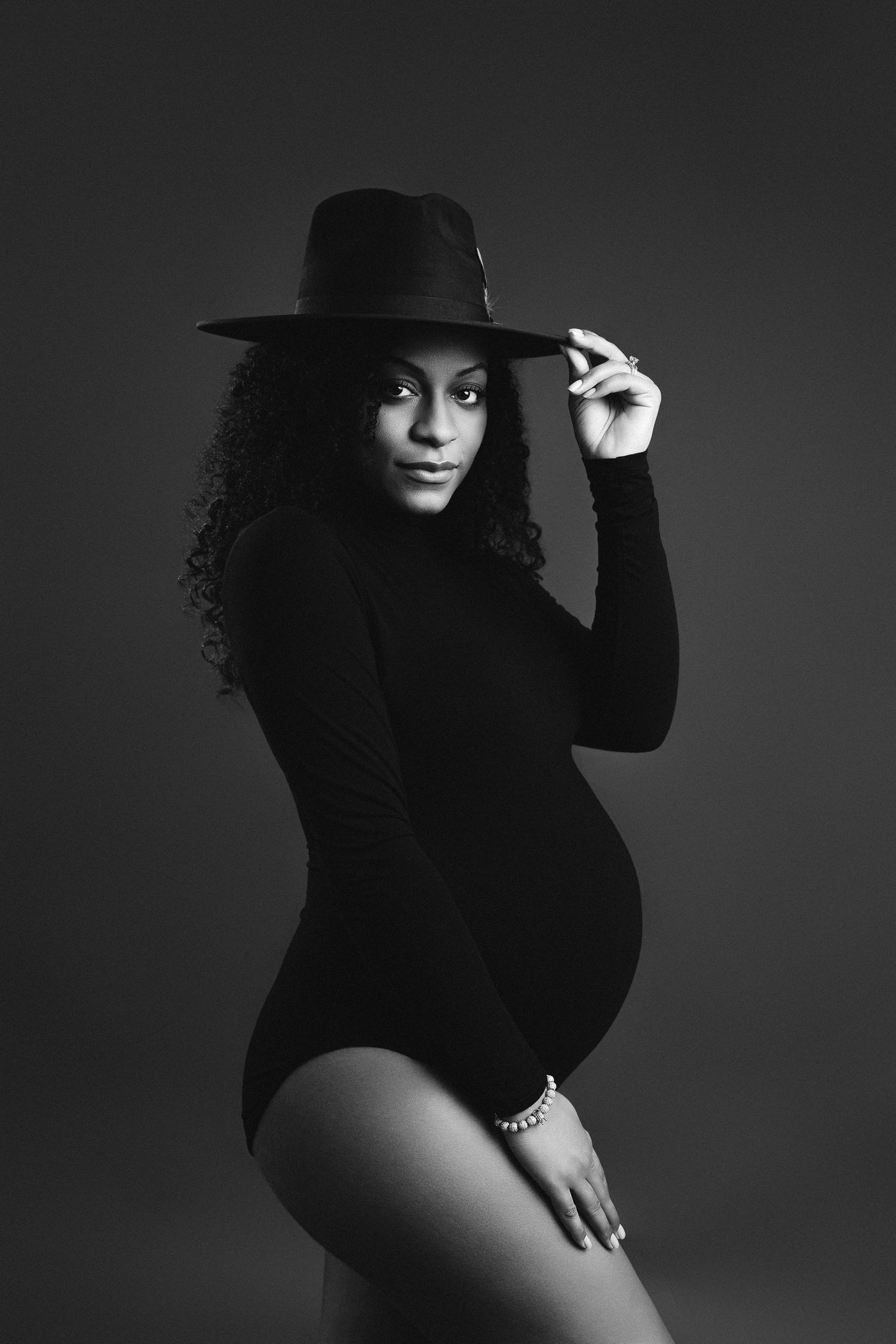 Dramatic black and white maternity photo with woman in hat and bodysuit. maternity photographer Paloma Schell Houston TX