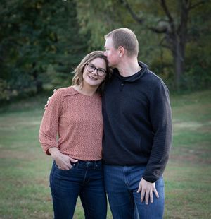 Couple posing together in a grassy park setting during golden hour.
