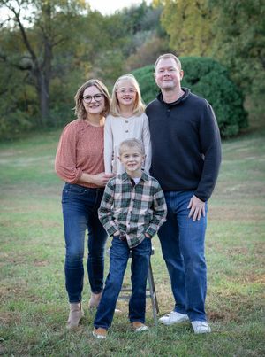 Family members standing together on a grassy hill during fall season.