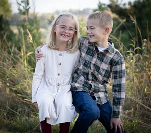 Children playing and laughing together in tall grass during an autumn photoshoot.