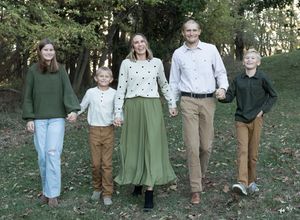 Family members walking together on a path through autumn trees wearing coordinated casual outfits.