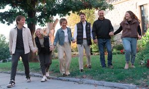Multiple people walking and posing together on a paved outdoor path during autumn.