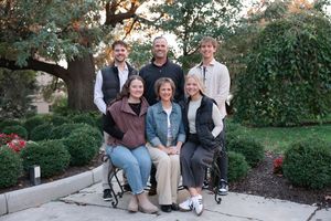 Candid outdoor family photo session with people sitting and standing on stone steps.
