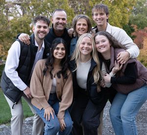 Group photo with people laughing and embracing while wearing casual fall attire outdoors.