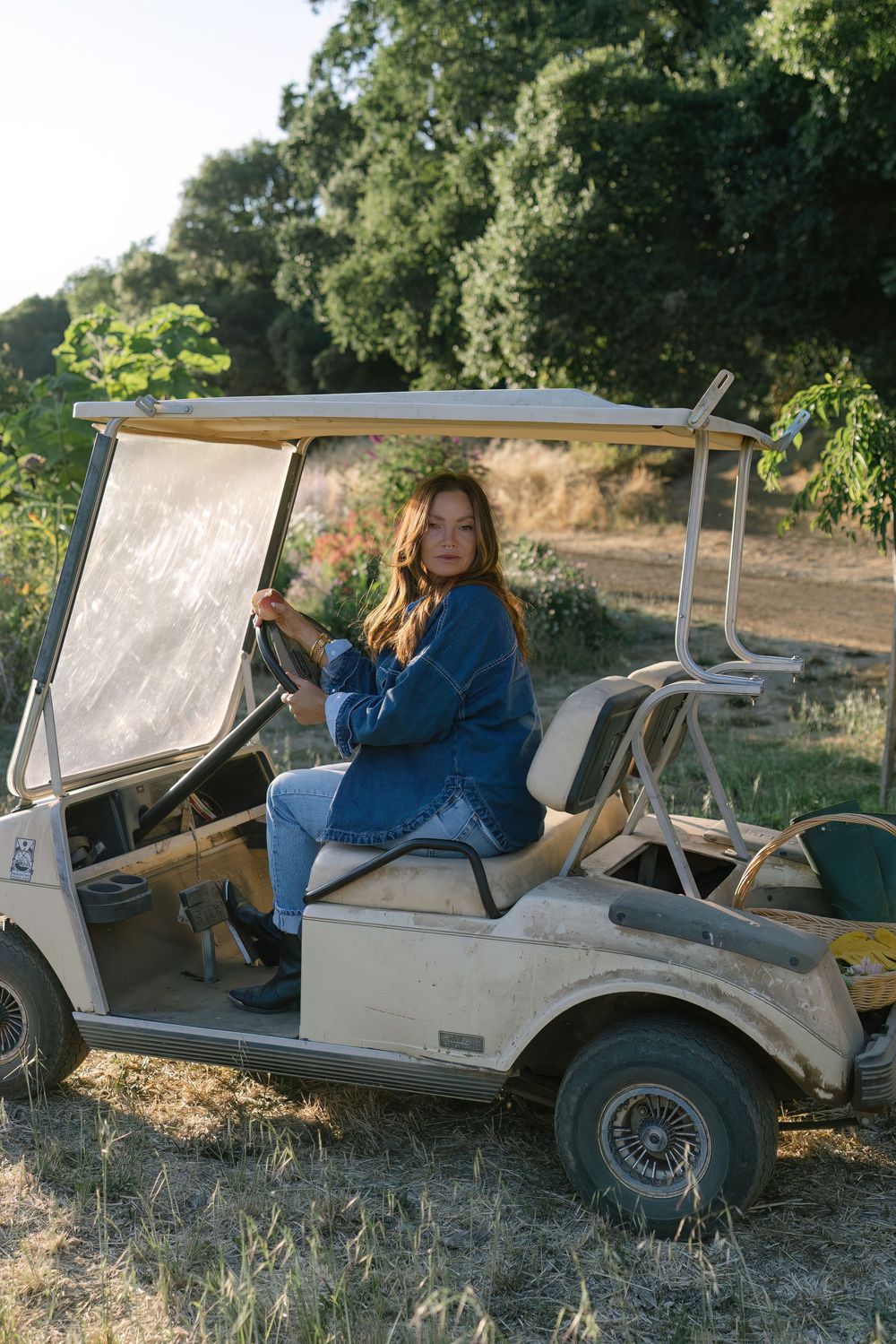 A golf cart parked on a dirt path surrounded by trees and natural vegetation.