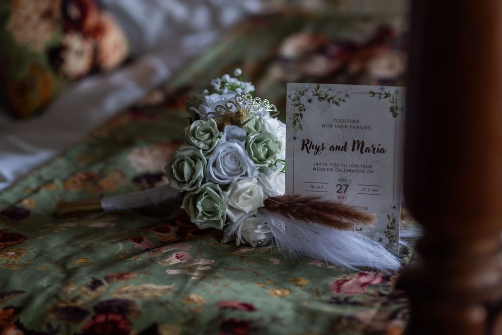 Delicate wedding details including paper invitations and soft floral arrangements on textured surface.