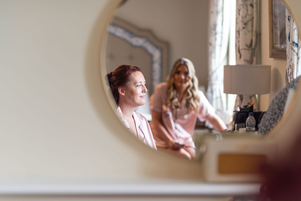 Couple shares a tender moment during their wedding preparations in a softly lit room.
