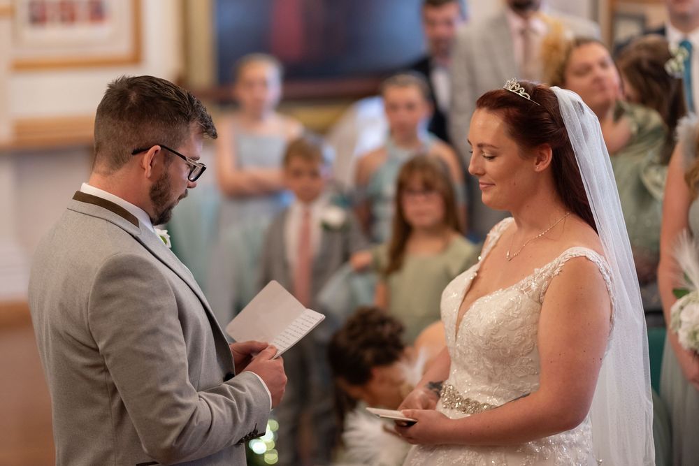 Wedding ceremony taking place in an elegant indoor venue with ornate decor.
