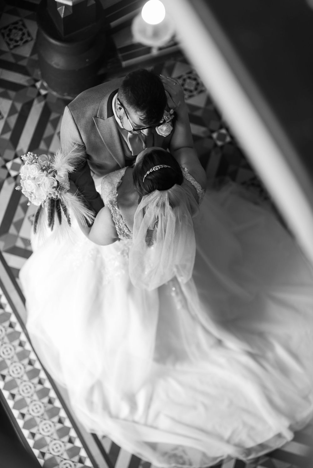 Overhead view of a bride in a flowing white gown on decorative floor tiles.