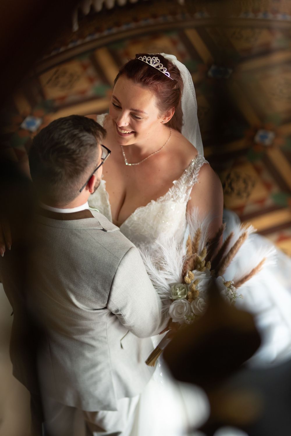 Close-up of newlyweds sharing a romantic moment under decorative ceiling.