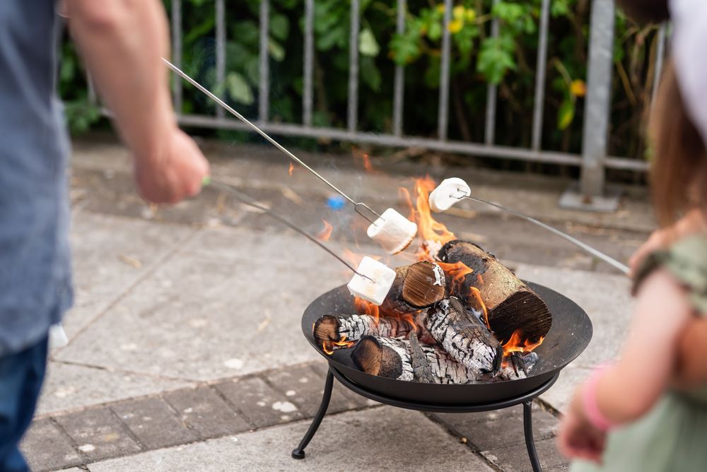 Fire pit with marshmallow roasting sticks during outdoor evening gathering.
