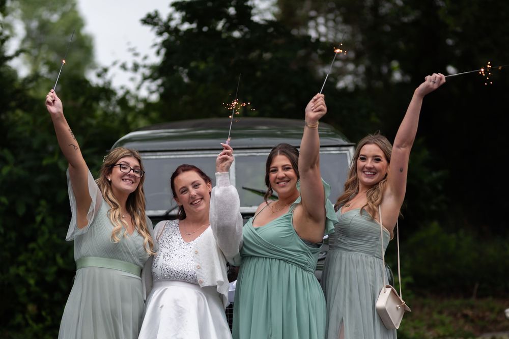 Wedding party in mint green bridesmaid dresses and white bridal gown celebrate joyfully outdoors.