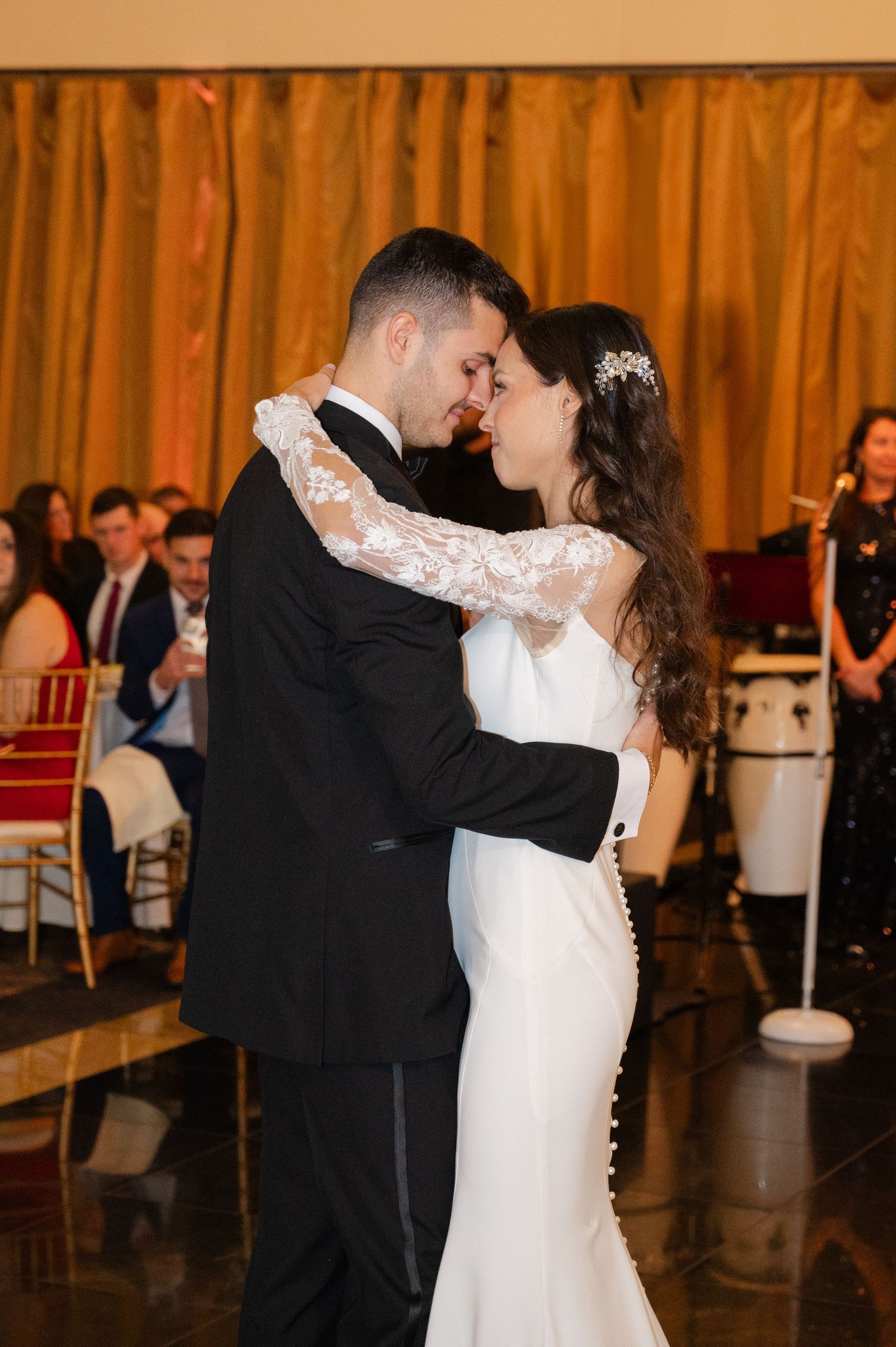 Newlyweds share their first dance at a wedding reception with orange curtains in the background at the Waterview in CT.