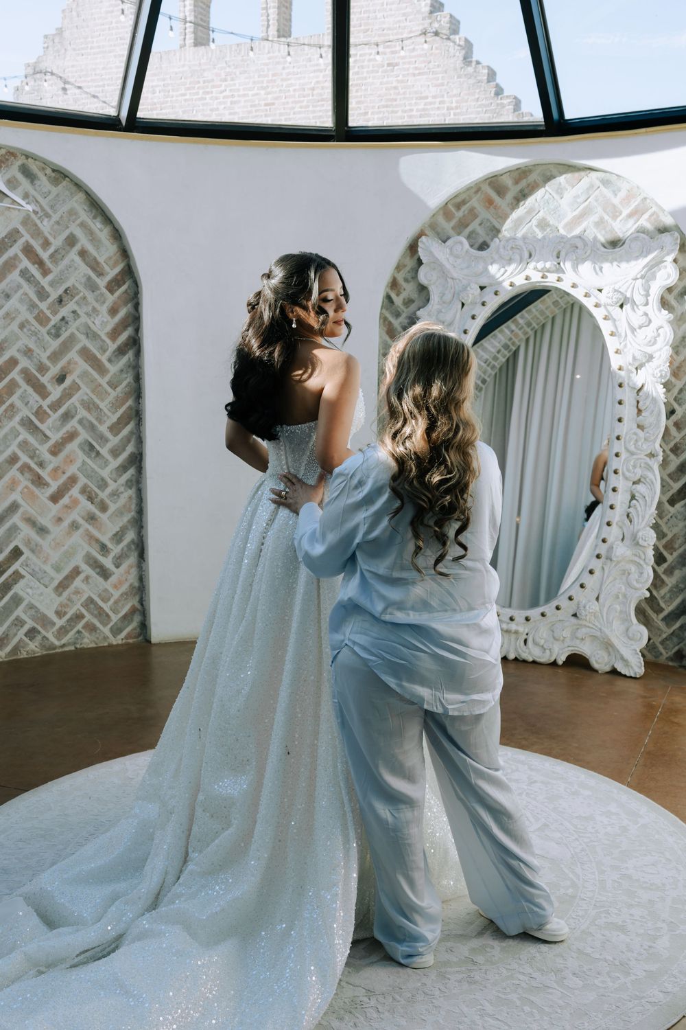 A wedding dress preparation scene with soft blue robes and flowing white gown in an elegant venue.