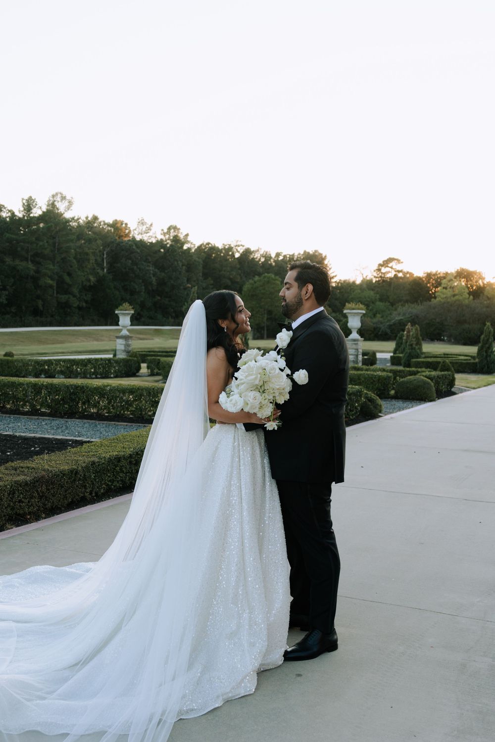 Newlyweds share romantic moments on an outdoor terrace with a flowing white wedding dress train.