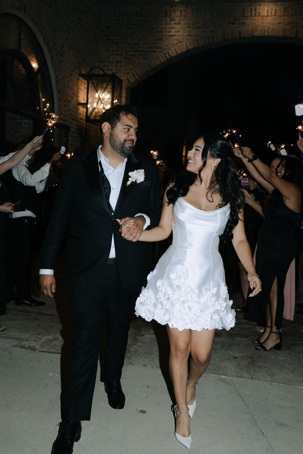 Newlyweds dancing energetically at their wedding reception in a brick-walled venue.