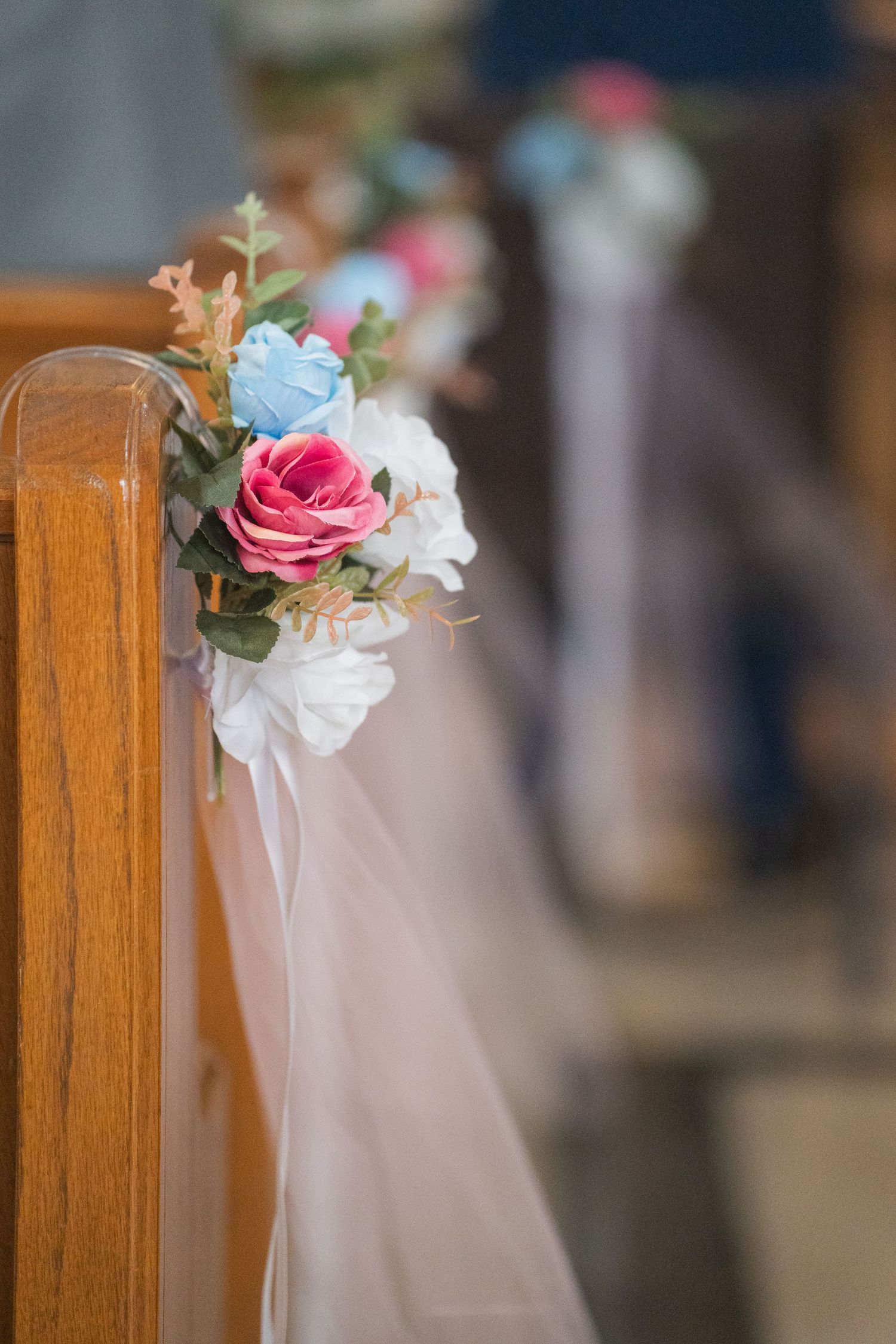 Church pew decorations featuring pink and white roses with flowing tulle ribbons.