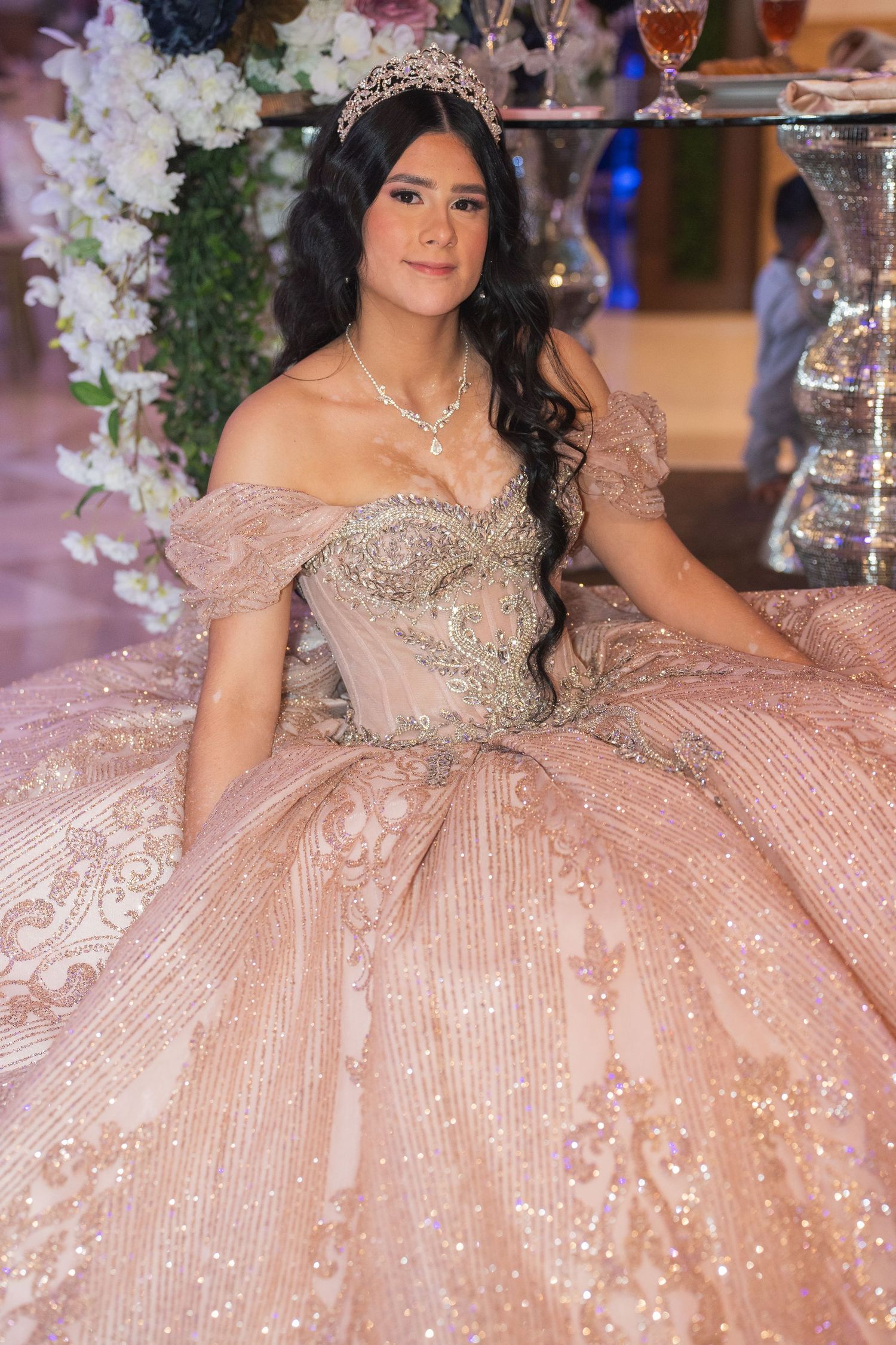 A sparkling champagne-colored ballgown with intricate beading and off-shoulder design.