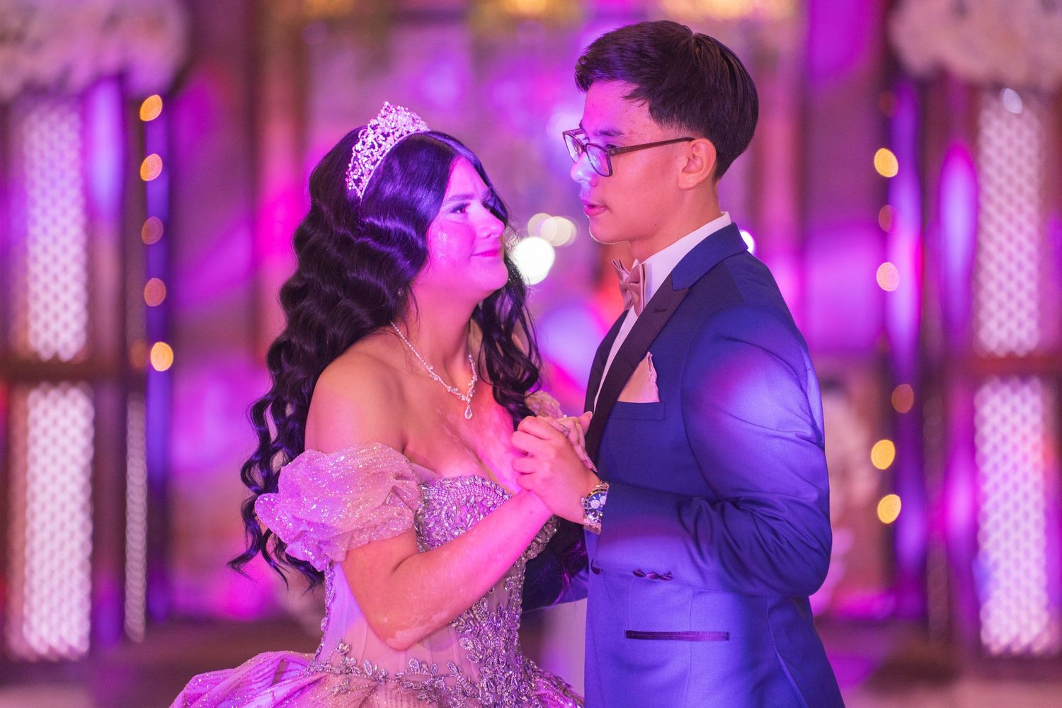 A quinceañera dance celebration with purple lighting and elegant formal attire.