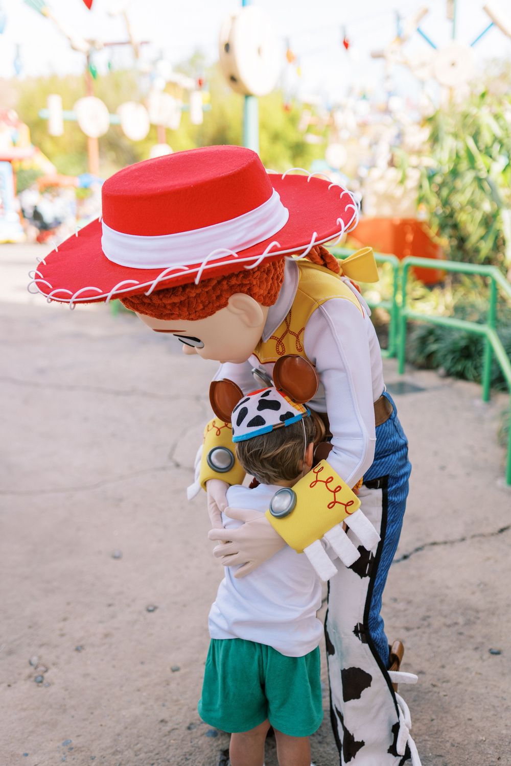 A Toy Story character gives warm hugs to kids at a themed park area with festive decorations.