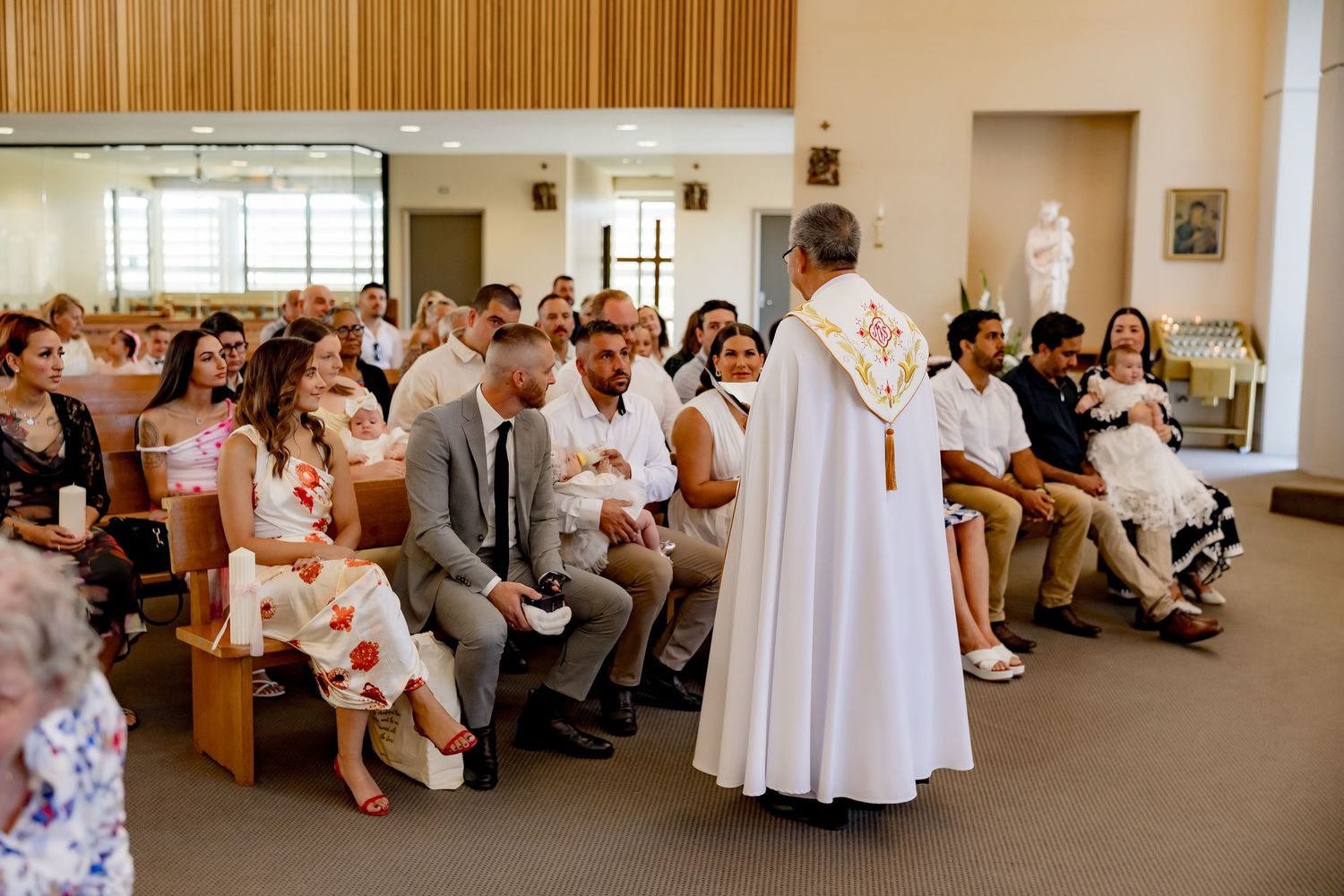 People seated in rows inside a wood-paneled room during a formal ceremony or gathering.