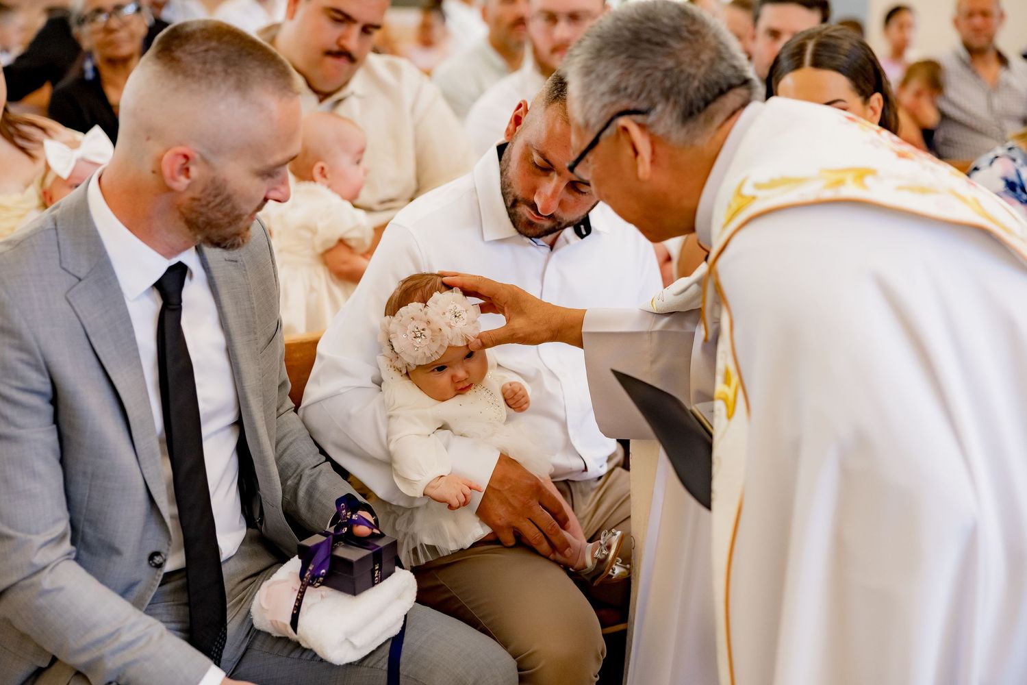 Religious ceremony taking place with priest and attendees in white robes.