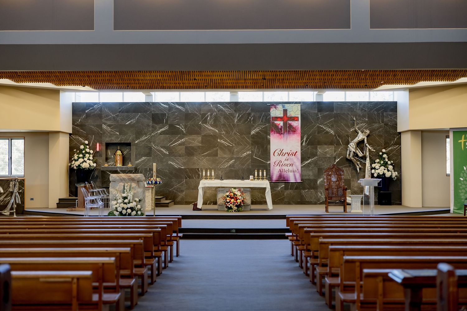 Interior view of modern church sanctuary with wooden pews and contemporary altar design featuring geometric wall art.