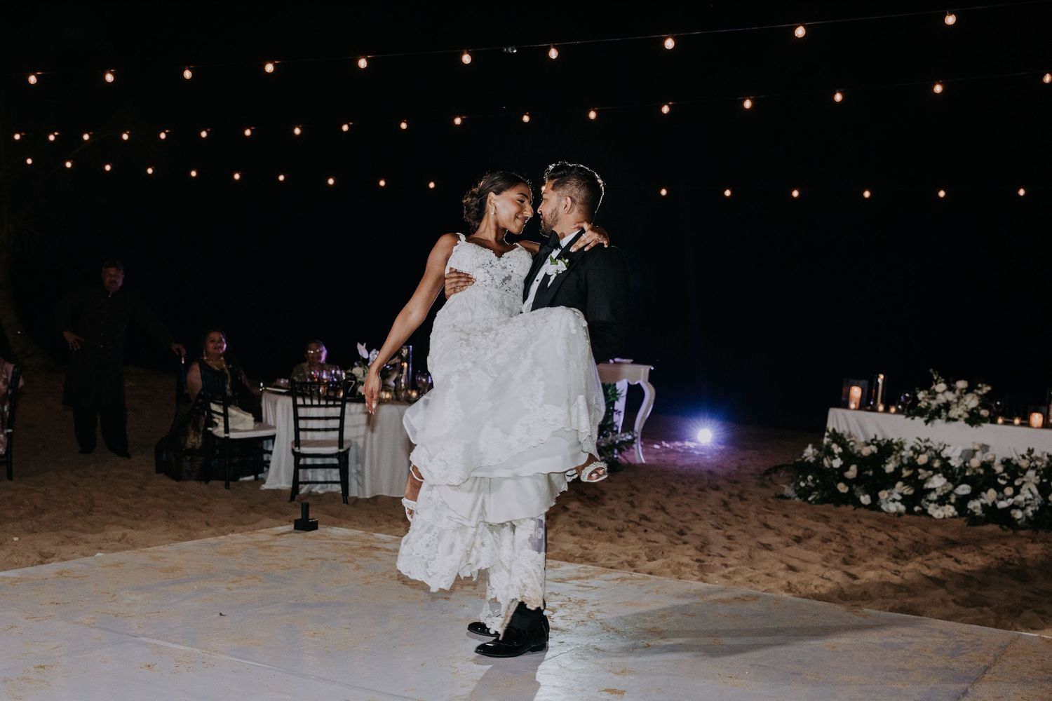 Wedding party performs choreographed dance number under string lights.