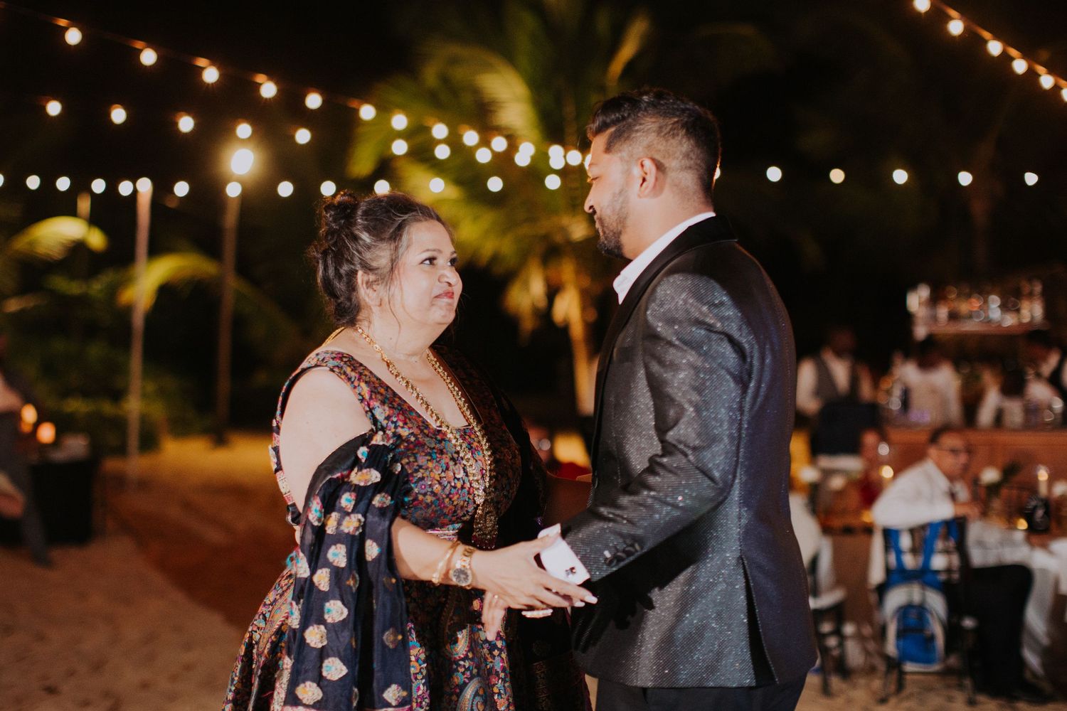 Outdoor wedding reception at night with string lights creating a romantic atmosphere.