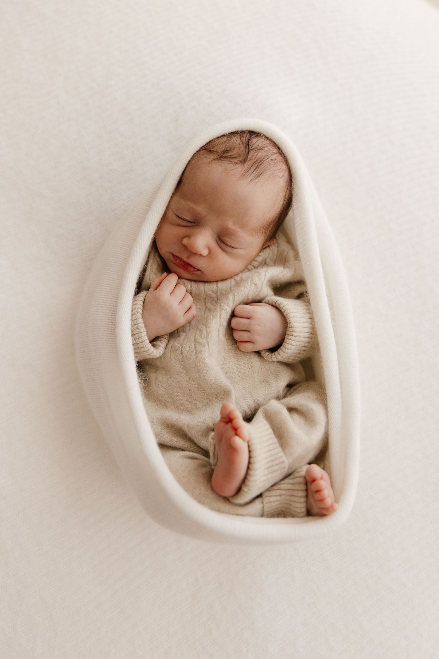 A sleeping newborn baby swaddled in cream-colored fabric lies peacefully in multiple similar poses.