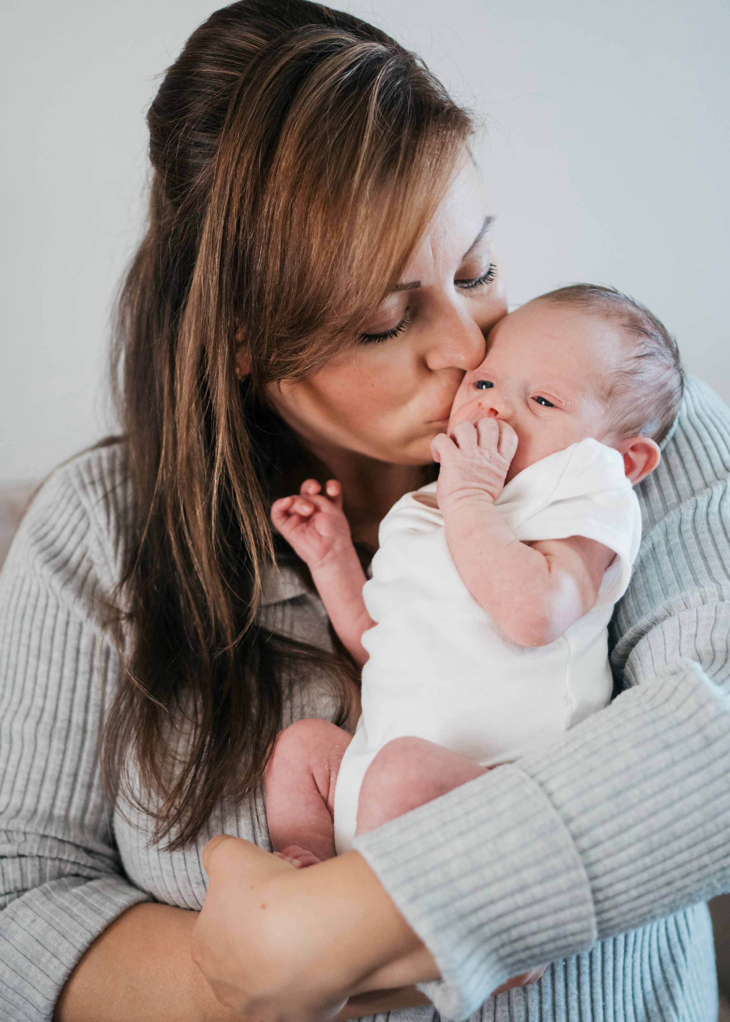 a mom and baby kiss for their newborn in home photography shoot